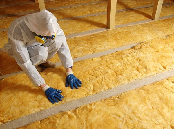 Aerolite insulation installer fitting yellow glasswool between timber roof members